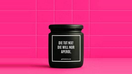 Duftkerze im Glas mit dem Aufdruck DIE TUT NIX! DIE WILL NUR APEROL, vor einer pinken Fliesenwand