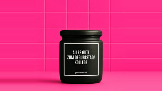 Duftkerze im Glas mit dem Aufdruck ALLES GUTE ZUM GEBURTSTAG! KOLLEGE, vor einer pinken Fliesenwand