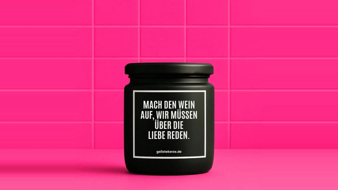 Duftkerze im Glas mit dem Aufdruck MACH DEN WEIN AUF, WIR MÜSSEN ÜBER DIE LIEBE REDEN, vor einer pinken Fliesenwand