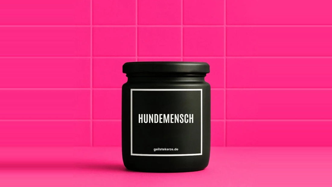 Duftkerze im Glas mit dem Aufdruck HUNDEMENSCH, vor einer pinken Fliesenwand