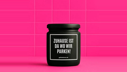 Duftkerze im Glas mit dem Aufdruck ZUHAUSE IST DA WO WIR PARKEN, vor einer pinken Fliesenwand