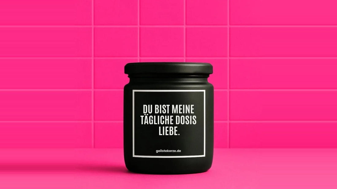 Duftkerze im Glas mit dem Aufdruck DU BIST MEINE TÄGLICHE DOSIS LIEBE, vor einer pinken Fliesenwand