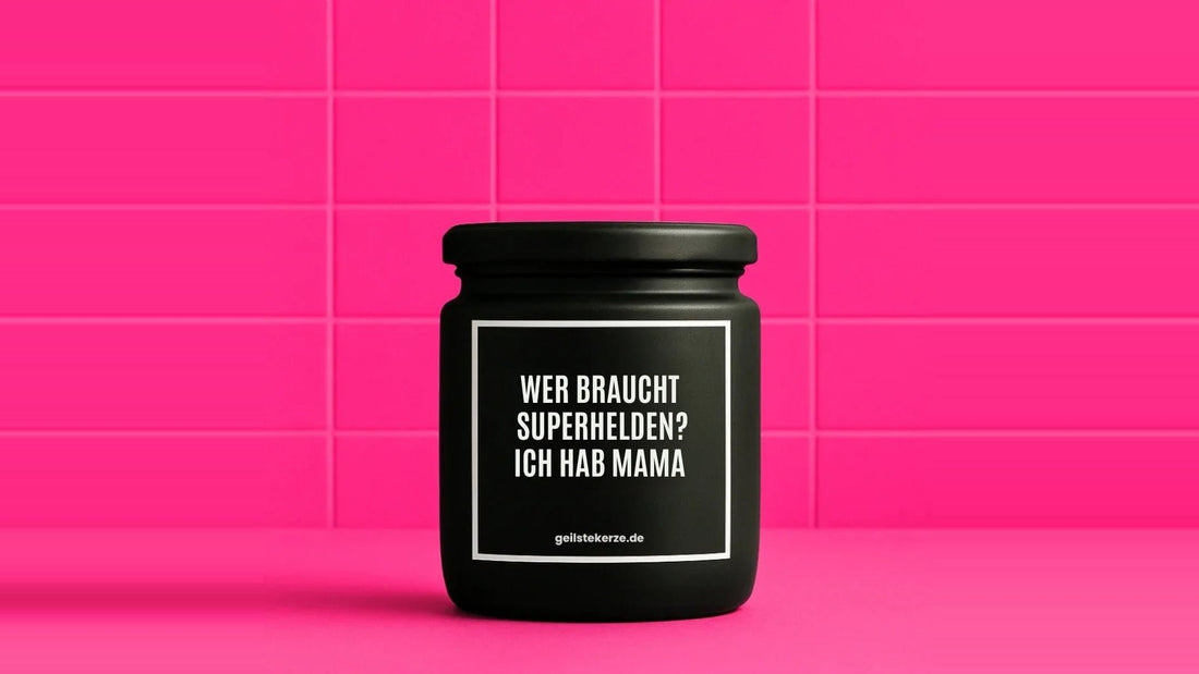 Duftkerze im Glas mit dem Aufdruck WER BRAUCHT SUPERHELDEN? ICH HAB MAMA, vor einer pinken Fliesenwand
