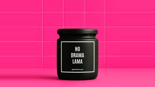 Duftkerze im Glas mit dem Aufdruck NO DRAMA LAMA, vor einer pinken Fliesenwand