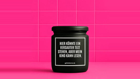 Duftkerze im Glas mit dem Aufdruck HIER KÖNNTE EIN VERSAUTER SPRUCH STEHEN, ABER MEIN KIND KANN LESEN, vor einer pinken Fliesenwand