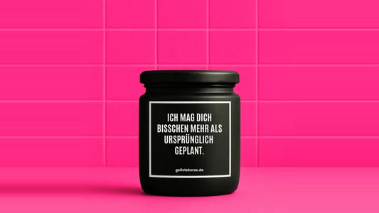Duftkerze im Glas mit dem Aufdruck ICH MAG DICH BISSCHEN MEHR ALS URSPRÜNGLICH GEPLANT, vor einer pinken Fliesenwand