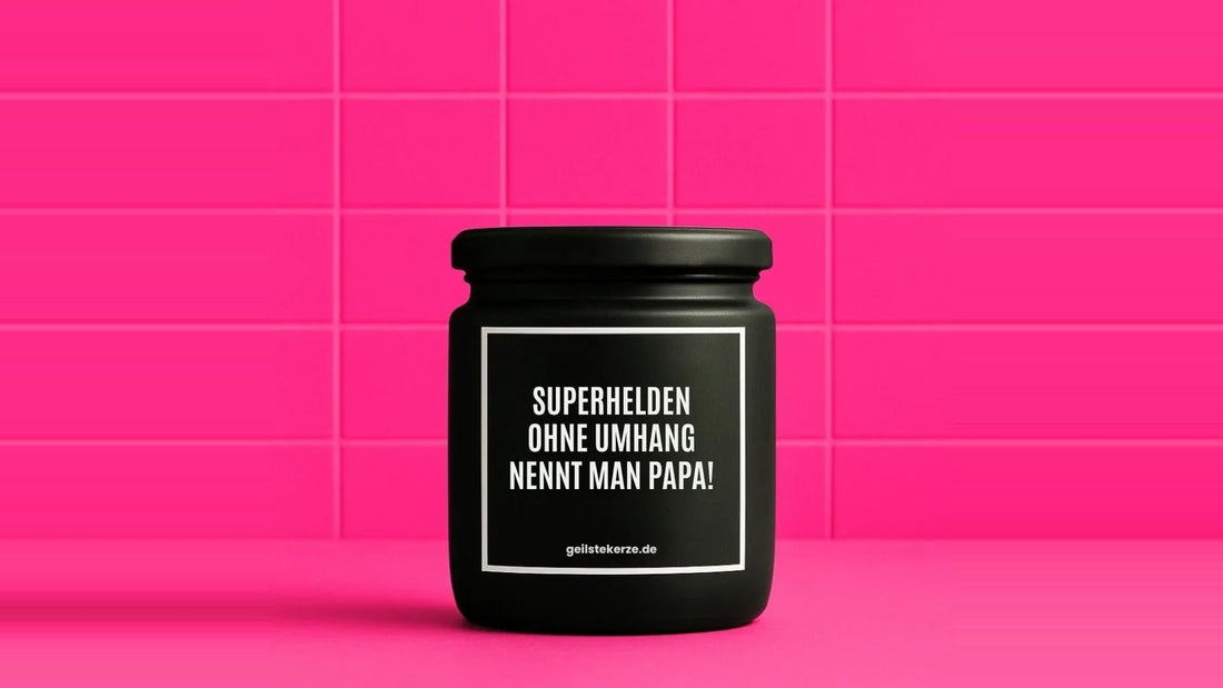 Duftkerze im Glas mit dem Aufdruck SUPERHELDEN OHNE UMHANG NENNT MAN PAPA, vor einer pinken Fliesenwand