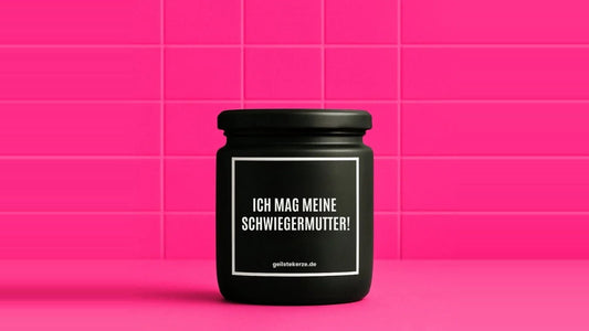 Duftkerze im Glas mit dem Aufdruck ICH MAG MEINE SCHWIEGERMUTTER, vor einer pinken Fliesenwand