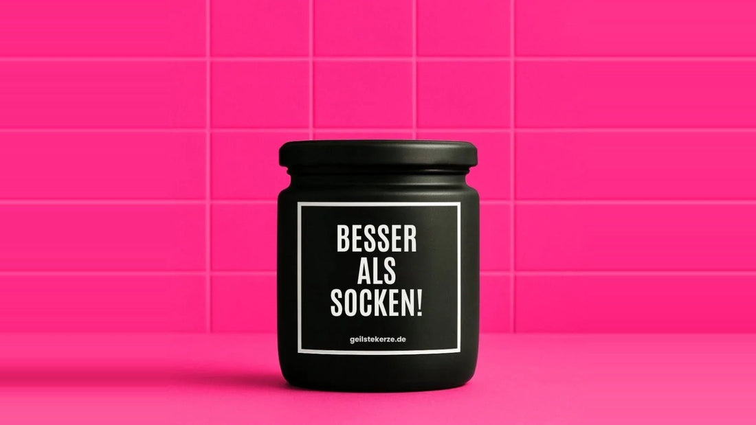 Duftkerze im Glas mit dem Aufdruck BESSER ALS SOCKEN, vor einer pinken Fliesenwand